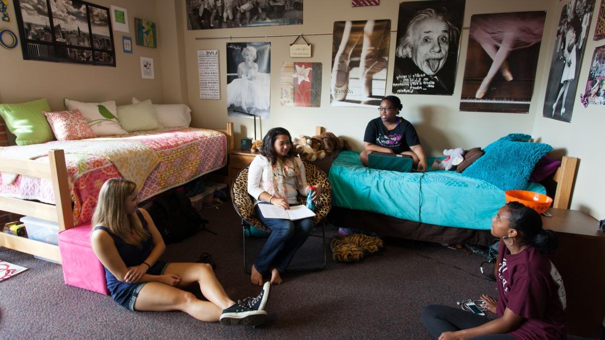 四名学生, 一个坐在床上，另外三个坐在他们宿舍的地板上聊天